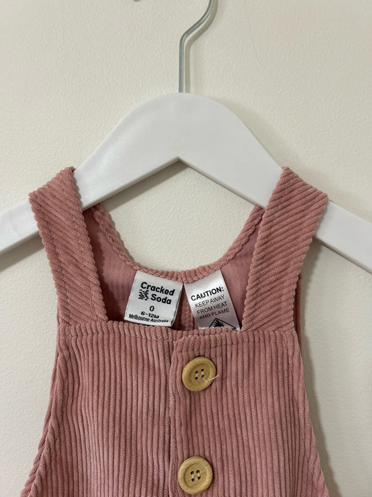 Pink striped overalls with buttons on a hanger against a white background