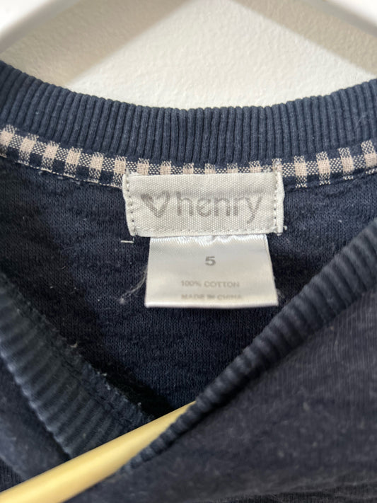 Navy blue textured sweater on a hanger against a white background