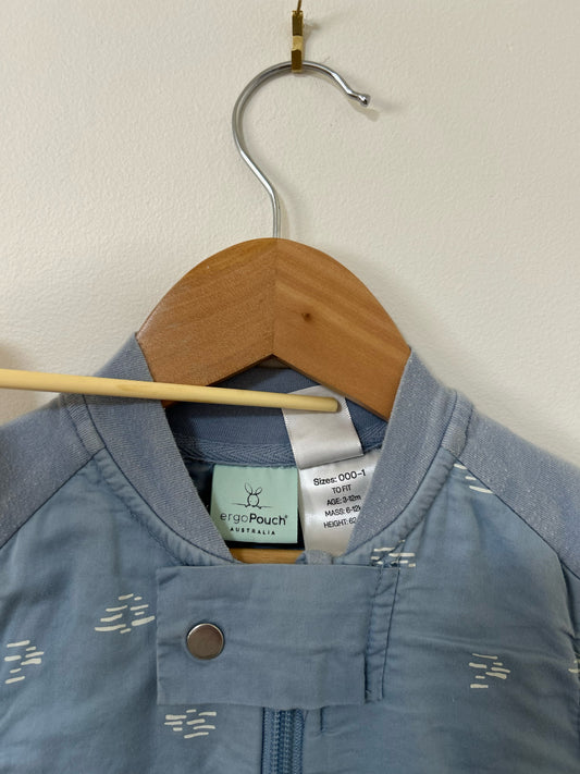 Blue sleeveless jacket with floral pattern on a hanger against a beige wall