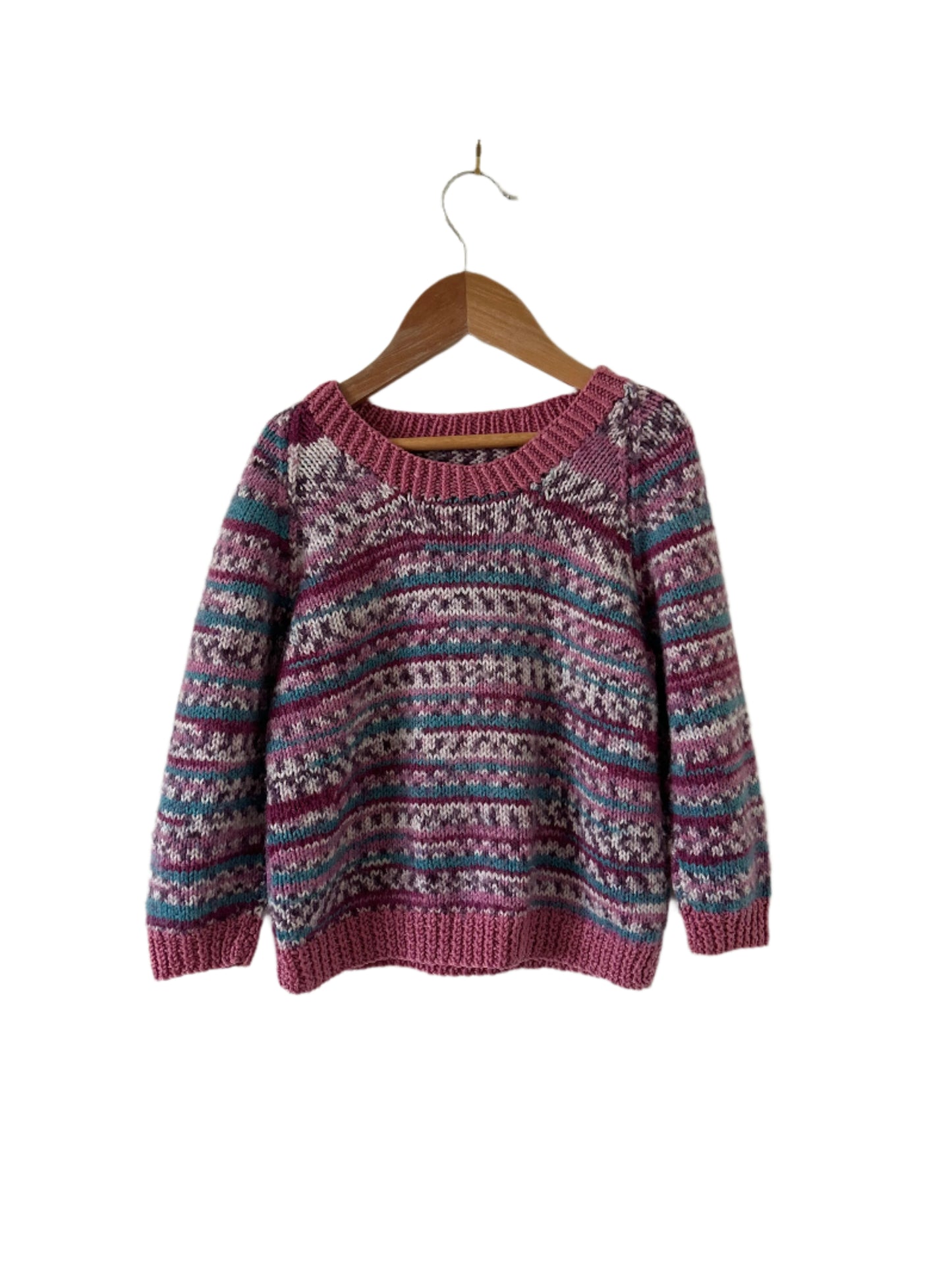 Knitted sweater with a pattern on a wooden hanger against a plain background