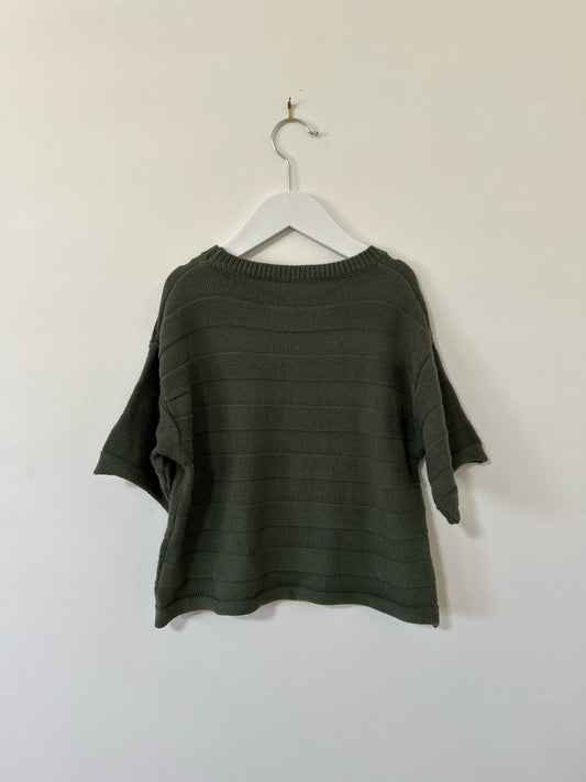 Green sweater on a hanger against a white background