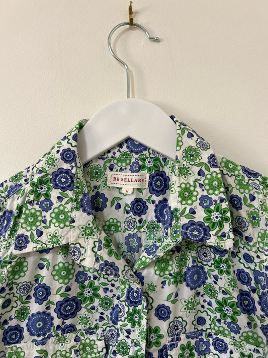 Floral patterned shirt on a hanger against a plain background