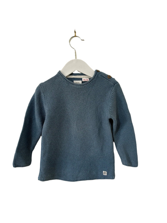 Blue sweater on a hanger against a beige background
