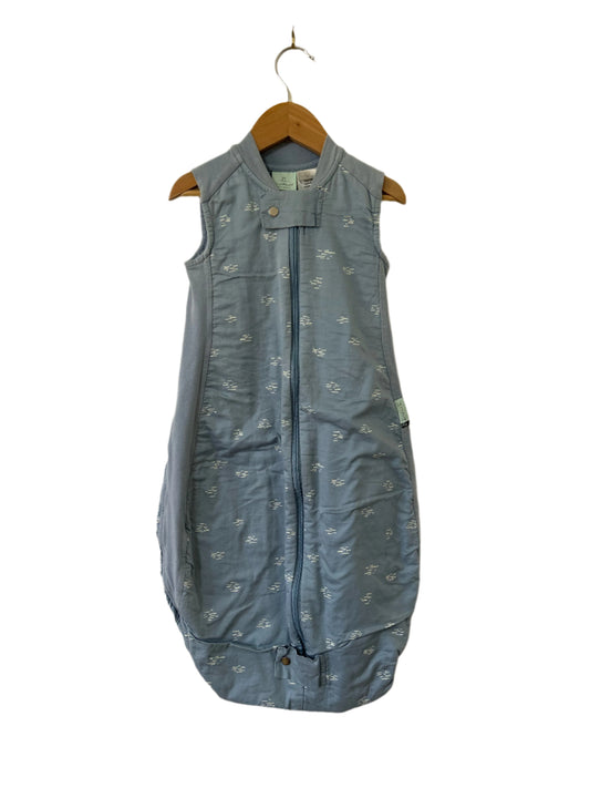 Blue sleeveless jacket with floral pattern on a hanger against a beige wall