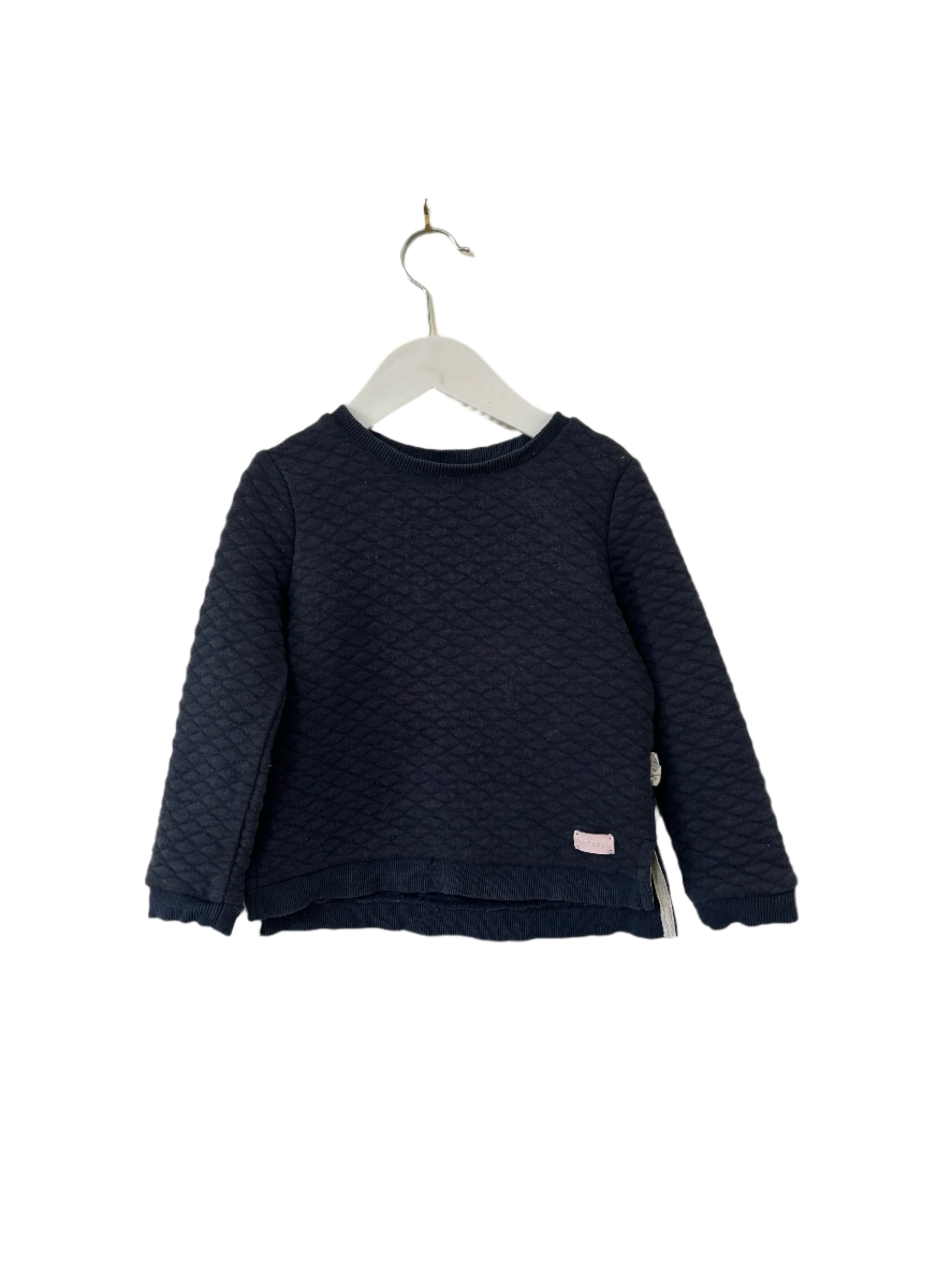 Navy blue textured sweater on a hanger against a white background