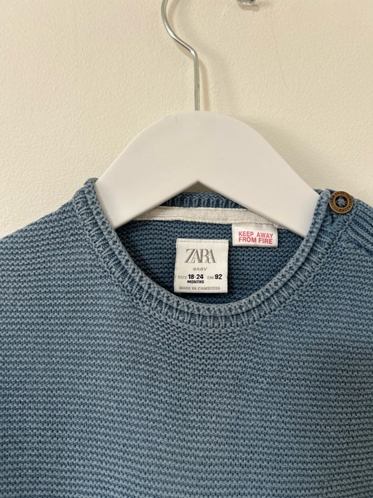 Blue sweater on a hanger against a beige background